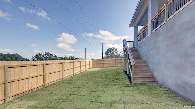 view of yard with stairs and a fenced backyard