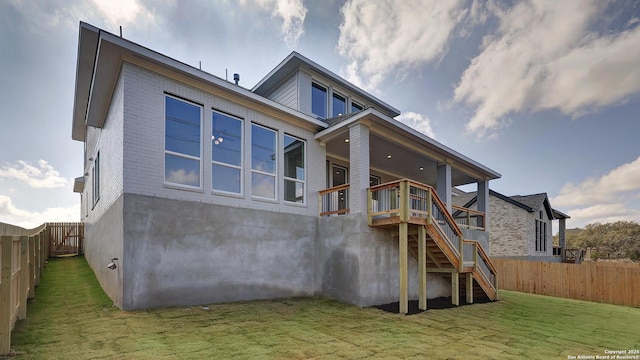 back of house with a fenced backyard, brick siding, a yard, stairway, and a wooden deck