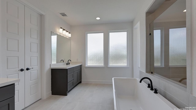 full bath featuring recessed lighting, a soaking tub, visible vents, vanity, and baseboards