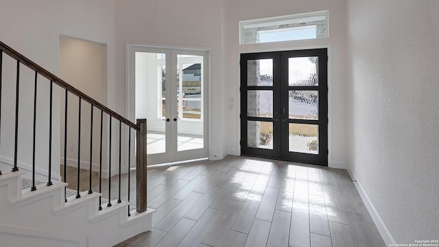 foyer featuring french doors, a healthy amount of sunlight, and stairway