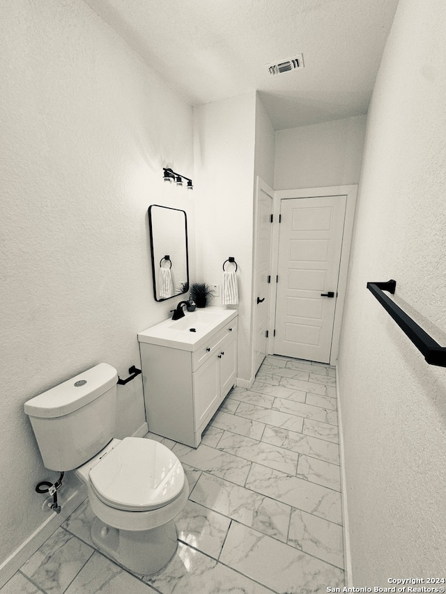 bathroom with toilet, a textured ceiling, and vanity