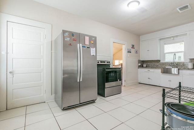 kitchen featuring tasteful backsplash, light tile patterned floors, sink, appliances with stainless steel finishes, and white cabinets