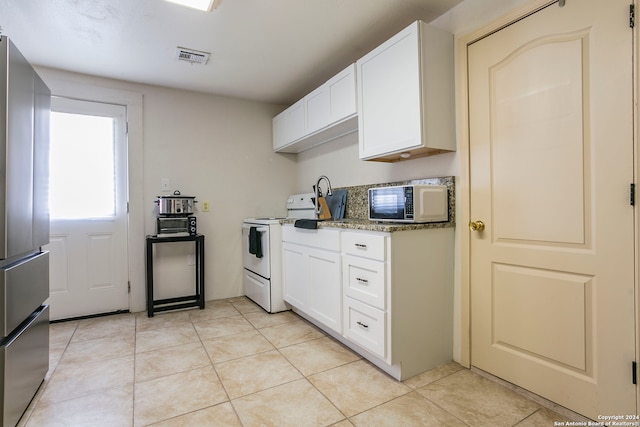 kitchen with white cabinets, light tile patterned floors, light stone countertops, white range with electric cooktop, and stainless steel fridge