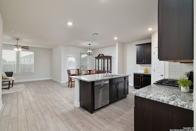 kitchen featuring ceiling fan with notable chandelier, sink, an island with sink, decorative backsplash, and stainless steel dishwasher