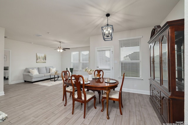 dining area featuring light hardwood / wood-style flooring and ceiling fan with notable chandelier