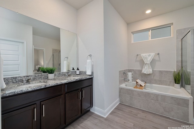 bathroom with plus walk in shower, wood-type flooring, and vanity