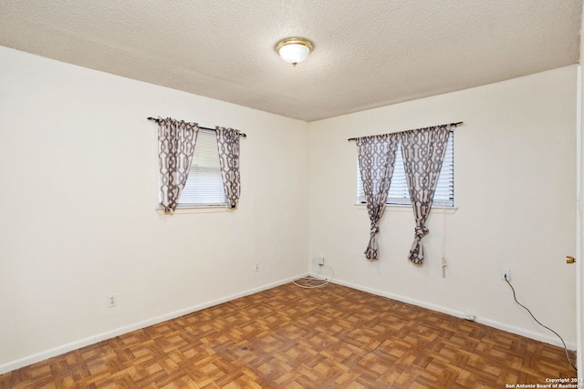 unfurnished room with a textured ceiling, plenty of natural light, and baseboards