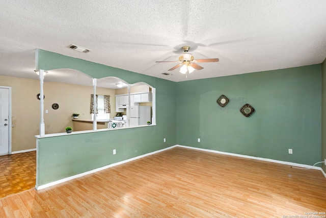 unfurnished living room featuring a textured ceiling, ceiling fan, and hardwood / wood-style floors