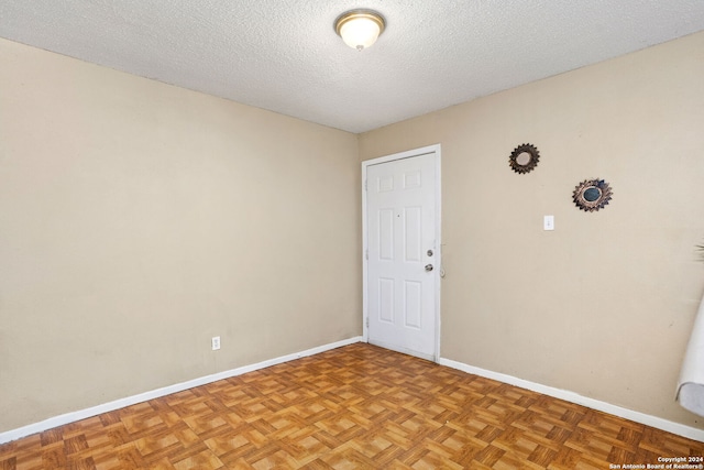 unfurnished room featuring a textured ceiling and baseboards