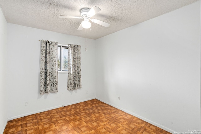 empty room with baseboards, a ceiling fan, and a textured ceiling