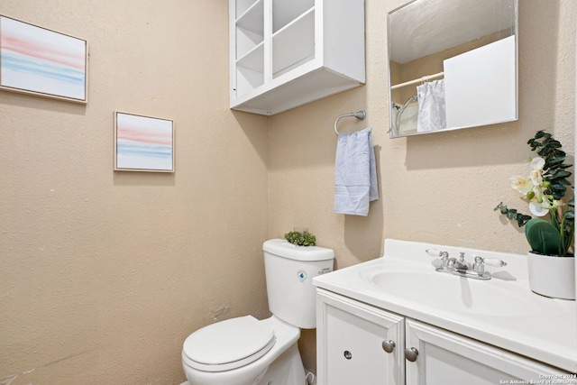 bathroom featuring a textured wall, vanity, toilet, and a shower with curtain