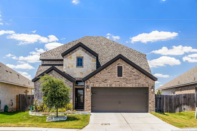 french country style house featuring a shingled roof, concrete driveway, brick siding, and fence