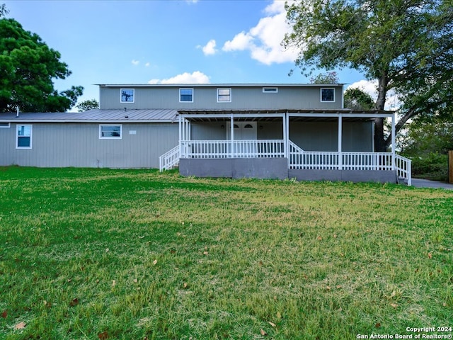 rear view of house featuring a lawn and a porch