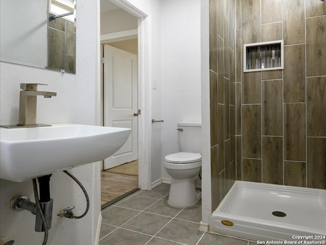 bathroom with tiled shower, wood-type flooring, and toilet