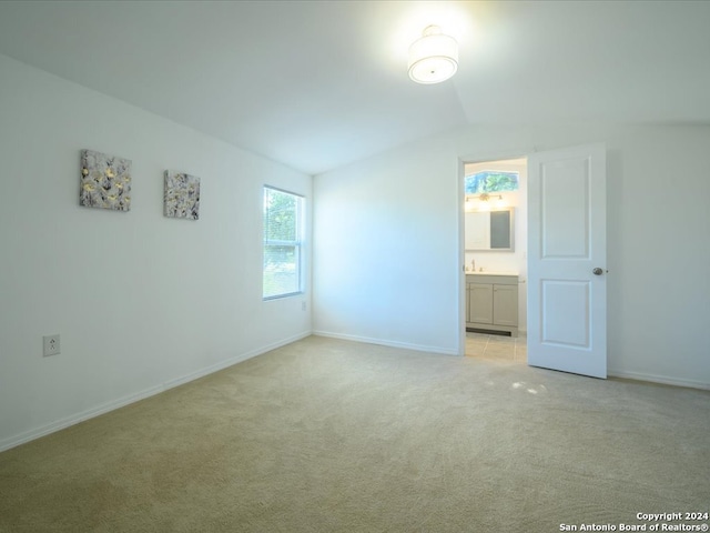 unfurnished bedroom with light carpet, vaulted ceiling, and connected bathroom