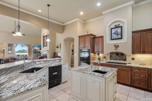 kitchen with tasteful backsplash, sink, an island with sink, and black double oven