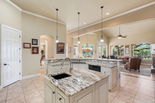 kitchen featuring light stone counters, ceiling fan, sink, pendant lighting, and a center island with sink