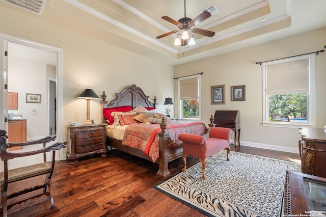 bedroom with ornamental molding, a tray ceiling, ceiling fan, and dark wood-type flooring