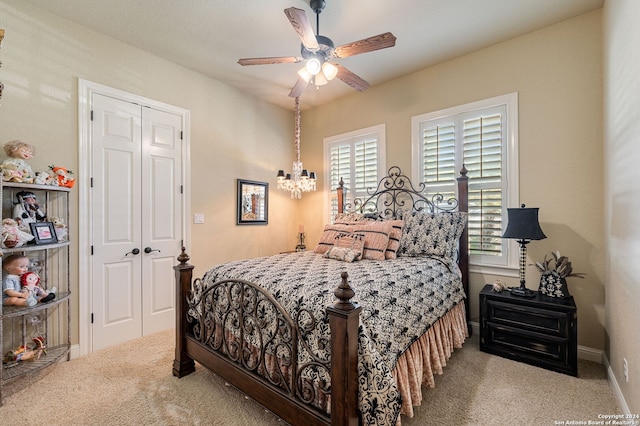 carpeted bedroom with multiple windows, ceiling fan with notable chandelier, and a closet