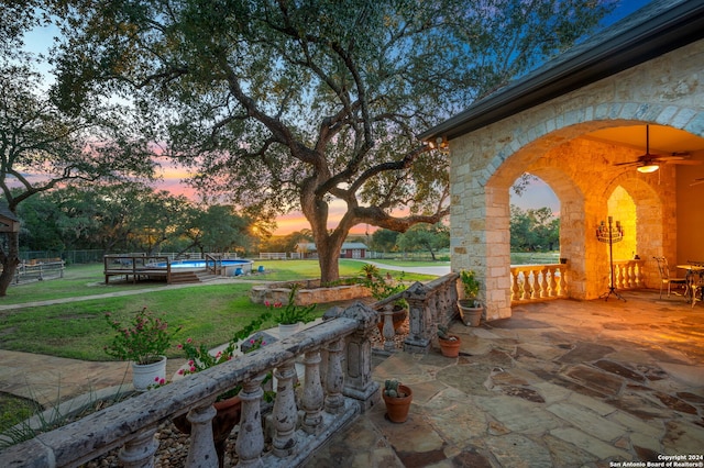 patio terrace at dusk with a lawn and a swimming pool