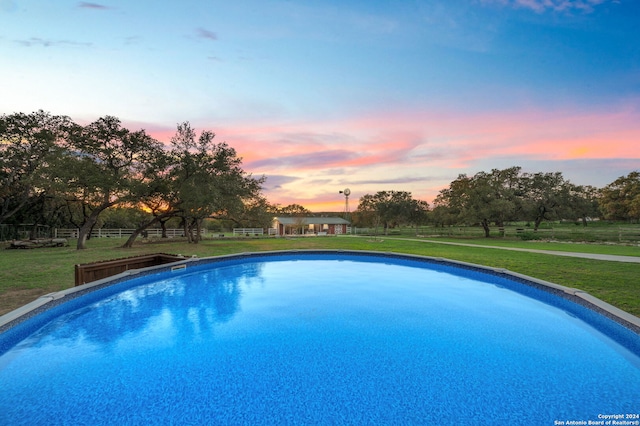 pool at dusk featuring a yard