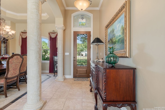 entrance foyer featuring ornate columns, crown molding, light tile patterned flooring, and a chandelier