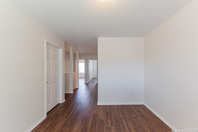 hallway with a textured ceiling and dark wood-type flooring