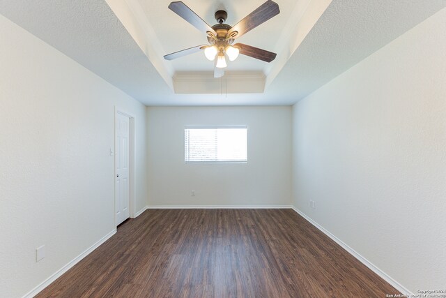 spare room with ceiling fan, a tray ceiling, and dark wood-type flooring