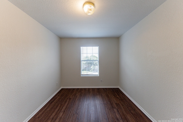 empty room featuring a textured ceiling and dark hardwood / wood-style floors