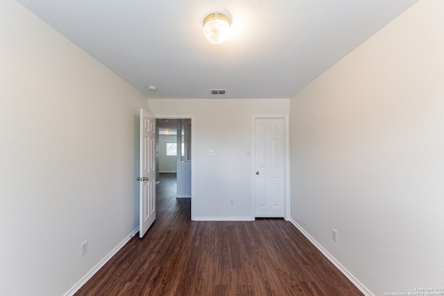 unfurnished bedroom with a textured ceiling and dark wood-type flooring