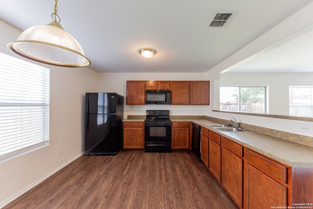 kitchen featuring black appliances, dark hardwood / wood-style floors, pendant lighting, and sink