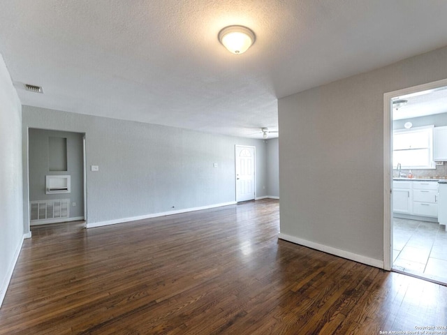 unfurnished room featuring dark hardwood / wood-style flooring, sink, and a textured ceiling