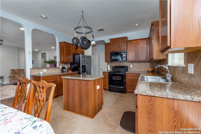 kitchen featuring black appliances, a kitchen island, a sink, and brown cabinetry