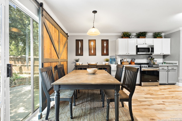 dining area featuring a barn door, light hardwood / wood-style floors, and ornamental molding