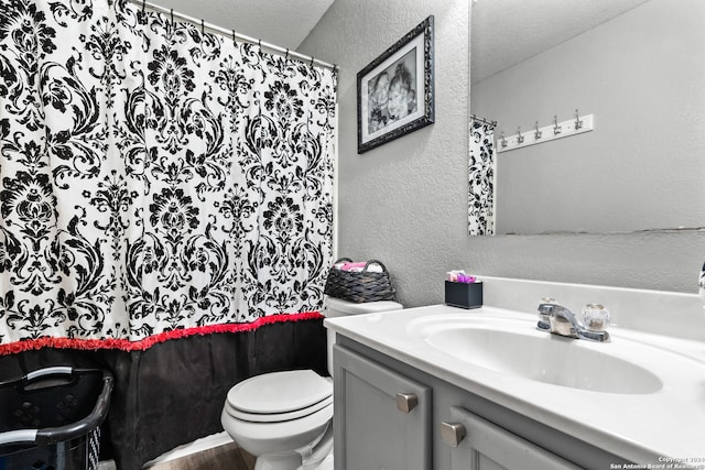 bathroom with vanity, toilet, and a textured ceiling