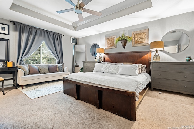 bedroom featuring a raised ceiling, ceiling fan, light carpet, and wooden walls