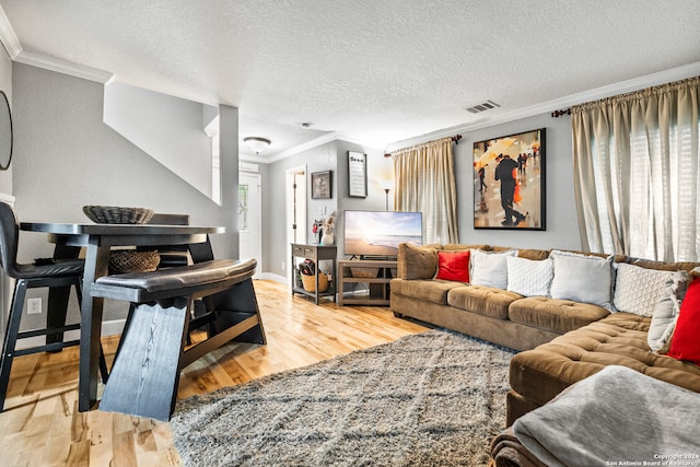 living room with a textured ceiling, crown molding, and light hardwood / wood-style flooring