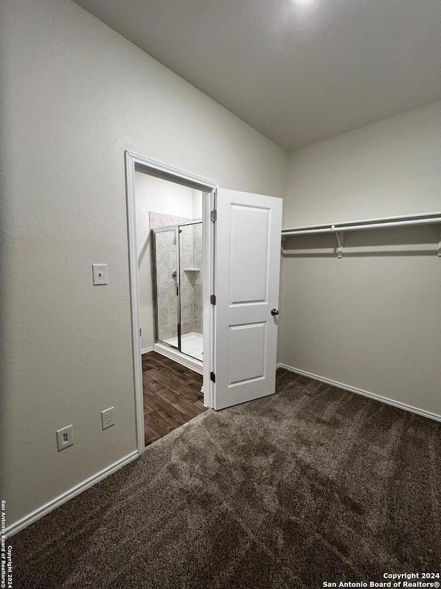 walk in closet featuring lofted ceiling and dark colored carpet