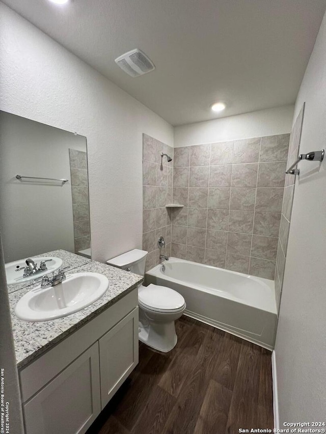 full bathroom featuring tiled shower / bath, vanity, toilet, and hardwood / wood-style flooring