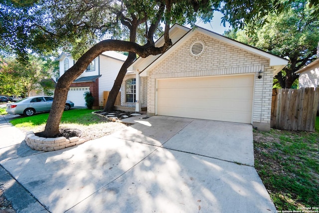 view of front of home with a garage, concrete driveway, brick siding, and fence