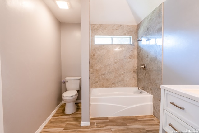 full bathroom with hardwood / wood-style floors, toilet, tiled shower / bath combo, and vanity