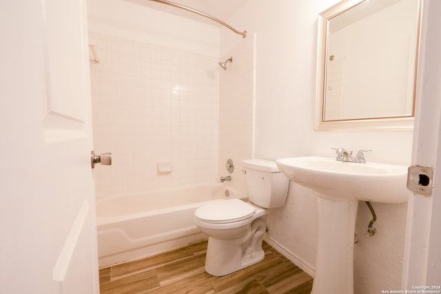 bathroom with tiled shower / bath combo, toilet, and wood-type flooring