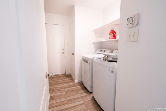 laundry room with light hardwood / wood-style flooring and washing machine and clothes dryer