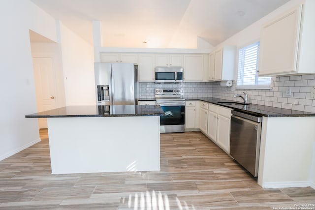 kitchen featuring dark stone countertops, appliances with stainless steel finishes, sink, lofted ceiling, and a kitchen island