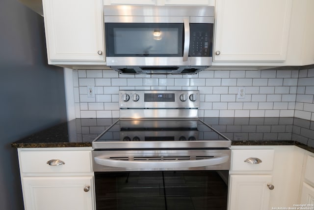 kitchen with dark stone countertops, white cabinetry, stainless steel appliances, and tasteful backsplash