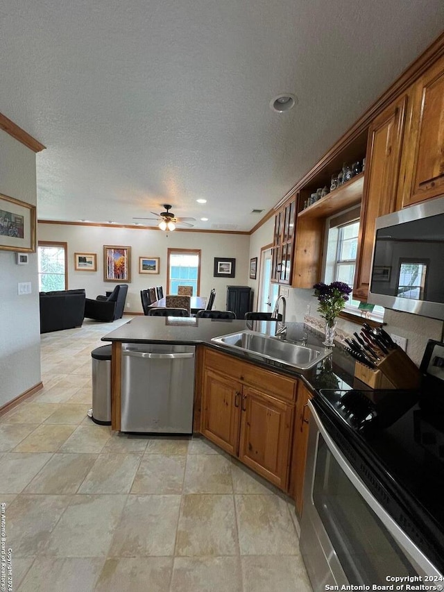 kitchen featuring stainless steel appliances, a textured ceiling, sink, ornamental molding, and ceiling fan