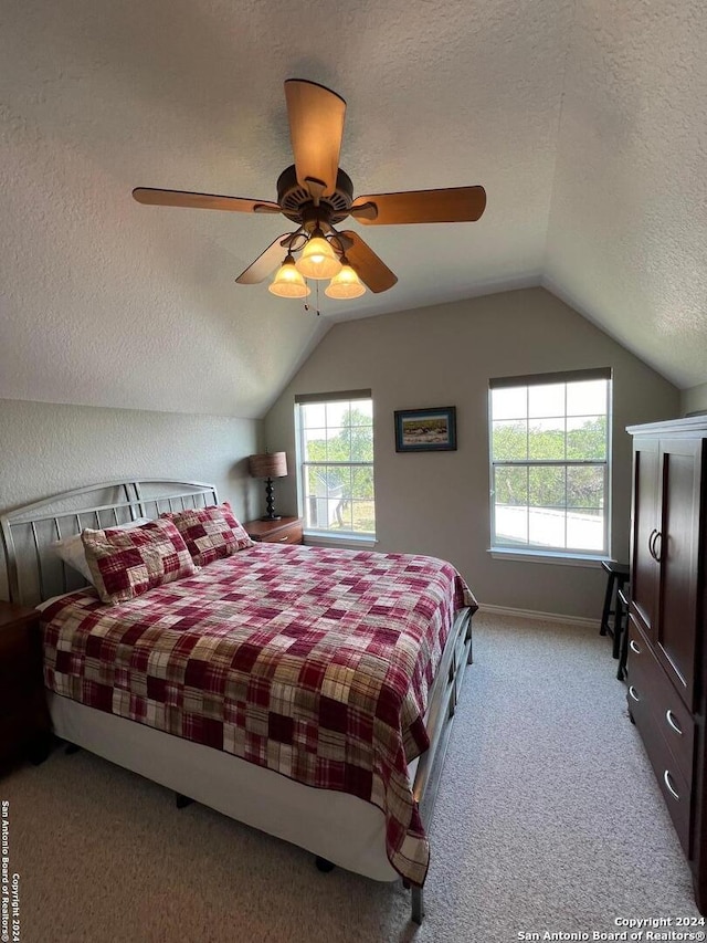 bedroom with lofted ceiling, a textured ceiling, ceiling fan, and light carpet