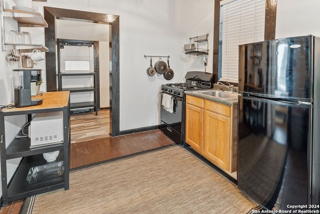 kitchen featuring black appliances, sink, and light wood-type flooring