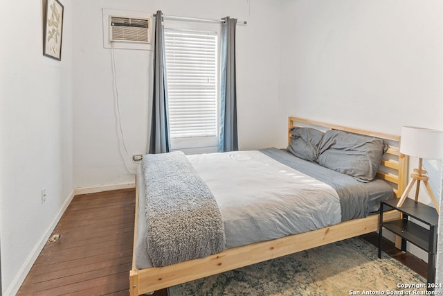 bedroom featuring dark wood-type flooring, an AC wall unit, and multiple windows