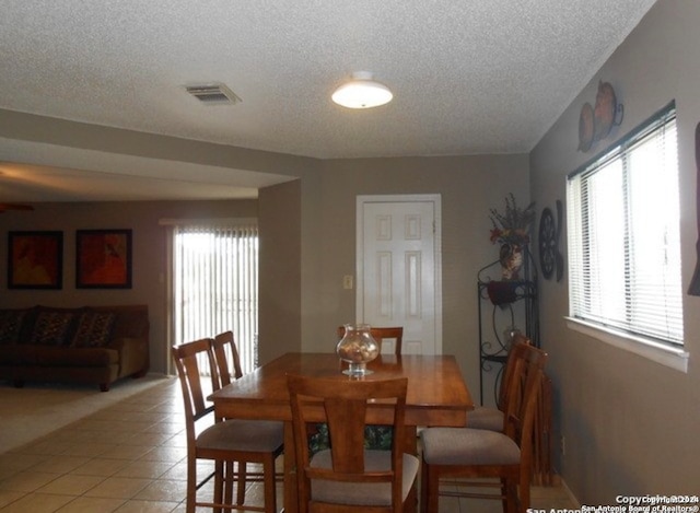 tiled dining area featuring a textured ceiling and a healthy amount of sunlight